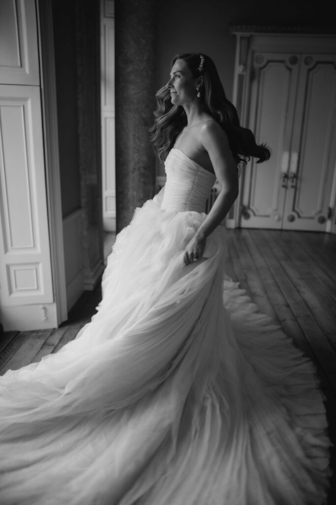 Black and white editorial photo of bride swishing her gown in a luxury wedding shoot.