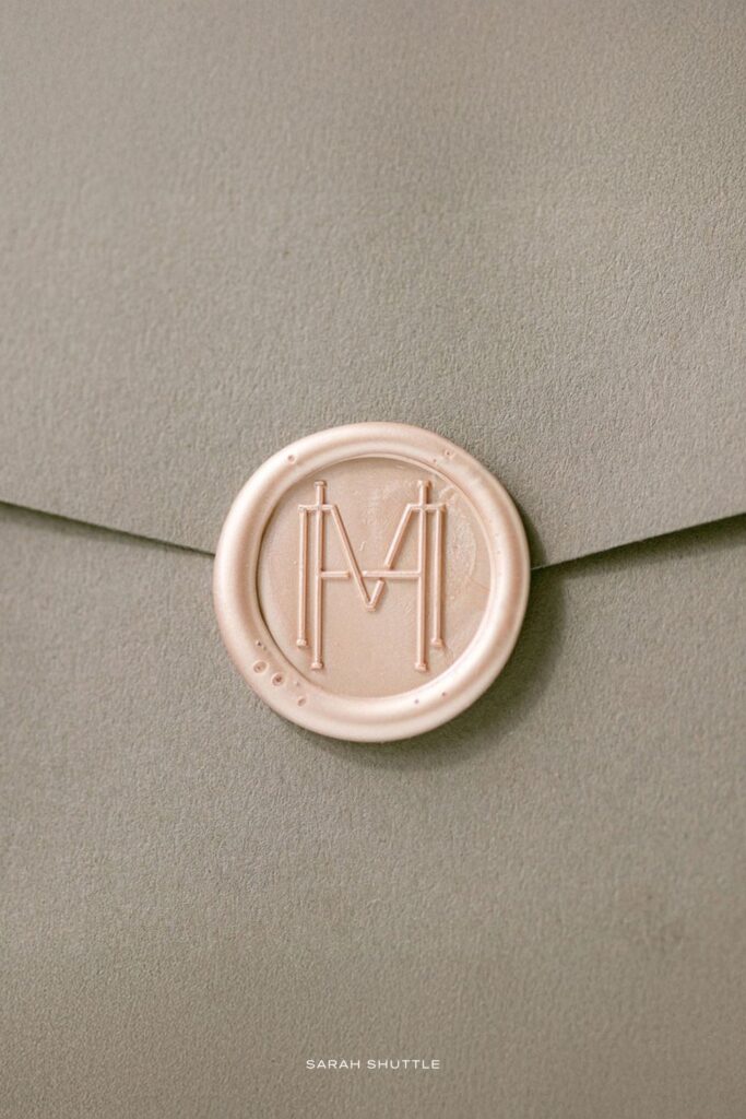 Blush pink wax seal with a modern monogram on warm taupe envelope, designed for a luxury cake designer brand.