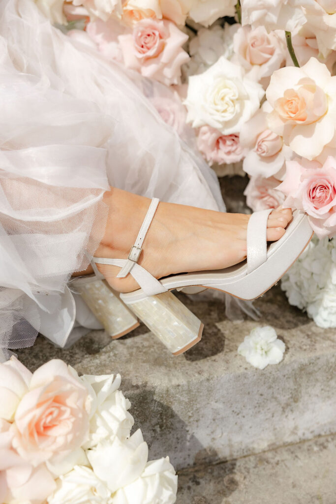 Bride with her bridal shoes surrounded by light airy modern florals in a hero brand shoot.