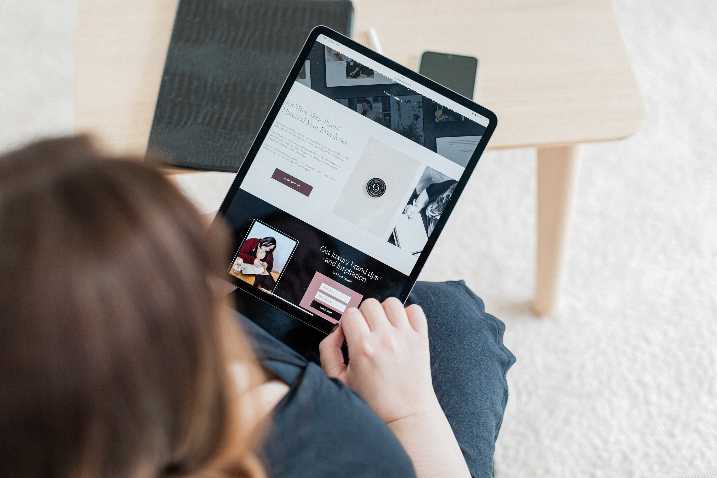 Sarah Shuttle, luxury brand designer, reviewing a website on an iPad screen — representing warm yet high-end branding.