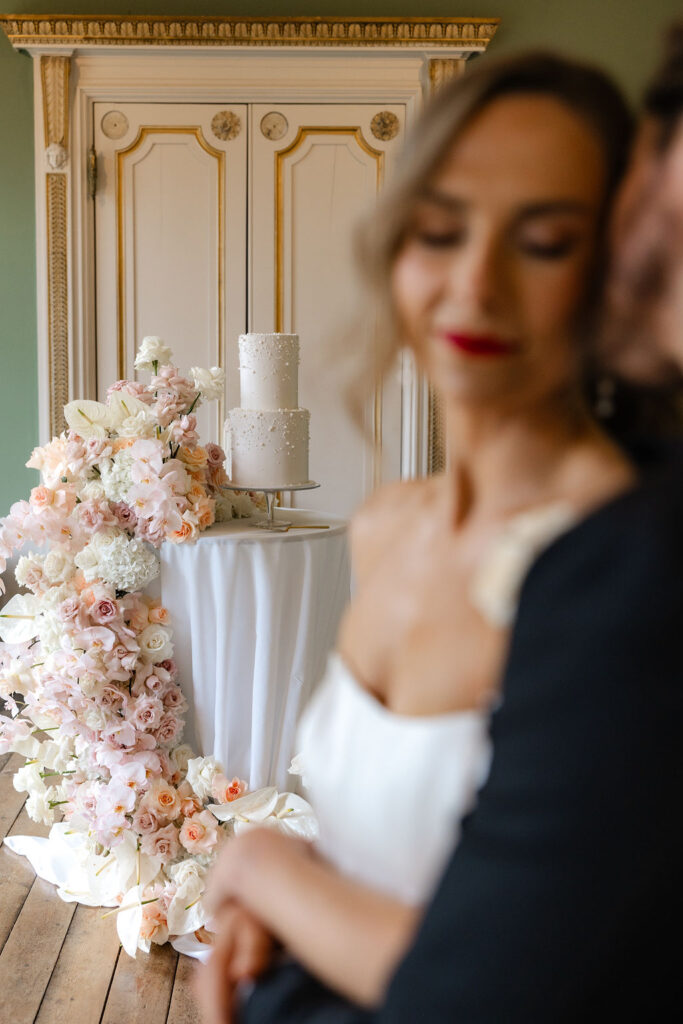 Luxury pearl wedding cake surrounded by cascading pastel florals in a styled shoot.