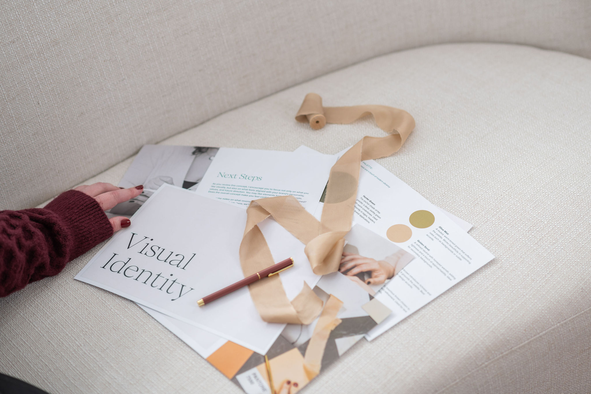 Luxury brand identity project documents laid out on a sofa during the design process
